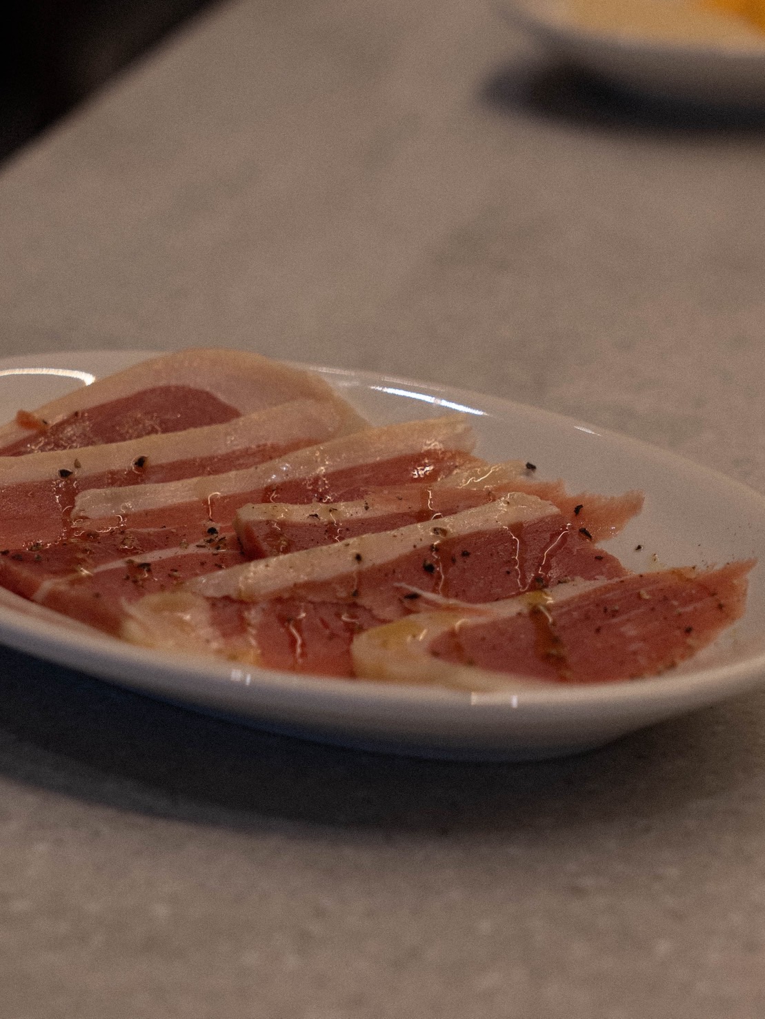 El jamón serrano de Bello Vero — jamón curado español cortado fino, con pimienta negra y aceite de oliva